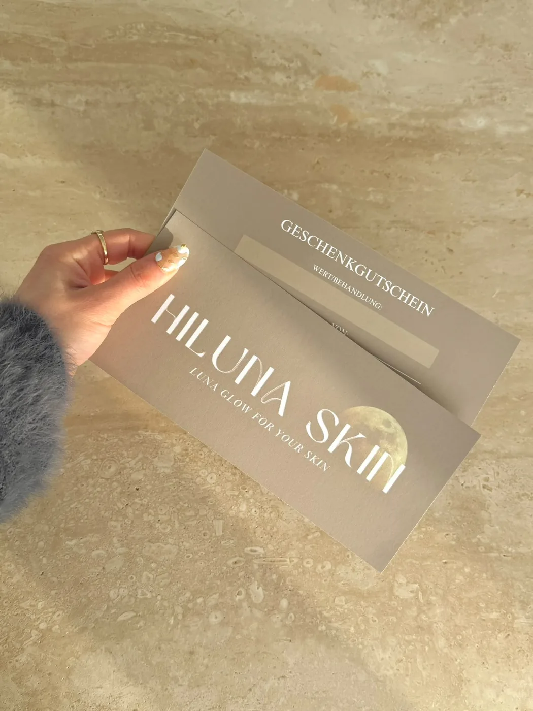 HilunaSkin Geschenkgutschein auf Travertin-Hintergrund