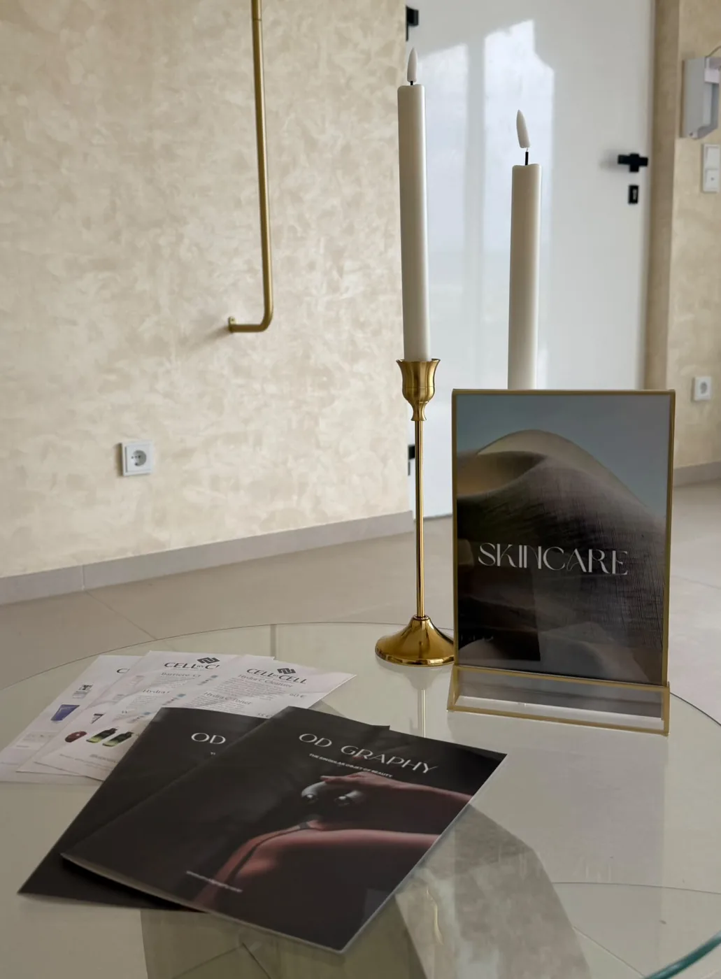 Lounge im Studio mit goldenen Kerzenständern und Skincare-Bilderrahmen